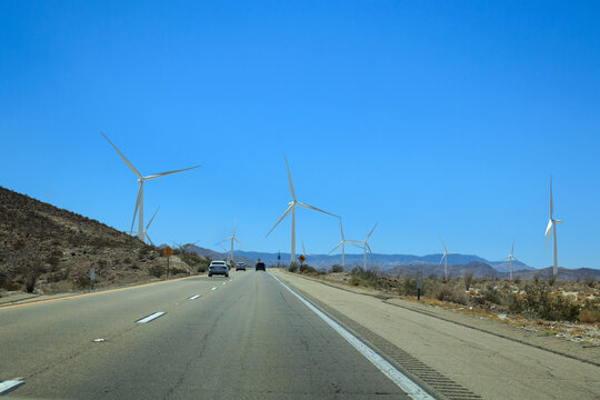 Desert wind turbines rising above rugged Imperial County hills beside westbound Interstate‑8 traffic under clear skies