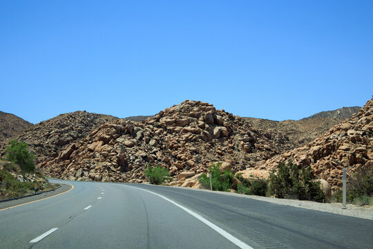 Curving Interstate-8 passes rocky desert hillside in Mountain Empire with bright blue sky, Southern California