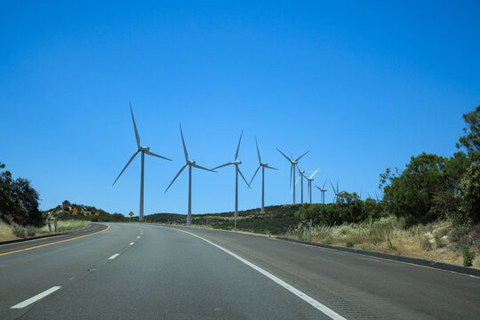 Renewable green energy wind farm with modern turbines along an empty asphalt Interstate-8 highway pass near Crestwood Summit in southeastern San Diego county, California; copy space