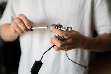 A person holds a car light and tools while working on it in a home or workshop setting © Mihail