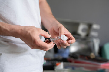 A person is holding a car light lamp part while fixing a vehicle in a garage during the day © Mihail