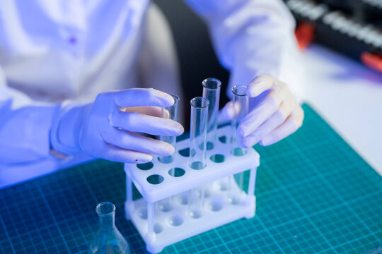 A person in a lab coat uses test tubes while working on vaccine research in a laboratory setting