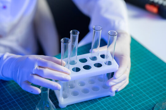 A person with gloves is handling a test tube rack in a laboratory setting while preparing for a vaccine experiment
