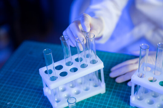 A person in gloves is sorting vaccine samples in a laboratory with test tubes and a green mat