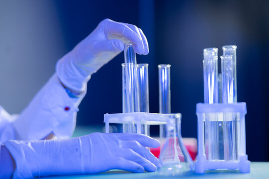 A hand carefully places a test tube into a holder while working on vaccine research in a lab