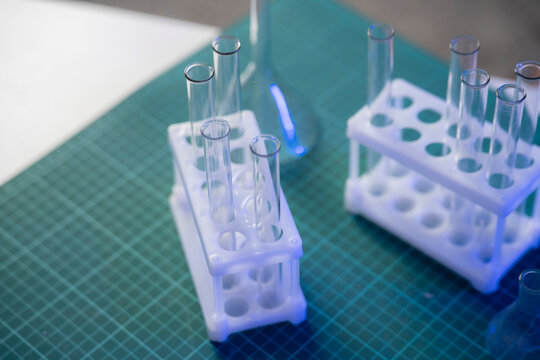 Test tubes are arranged in holders on a green grid surface within a laboratory where vaccines are prepared