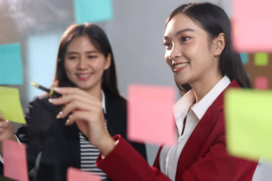 Businesswoman team brainstorming ideas using sticky notes in office.