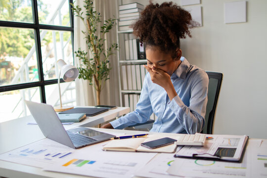 Stressed office worker feeling overwhelmed and frustrated. The woman in the office is sleepy and yawning.