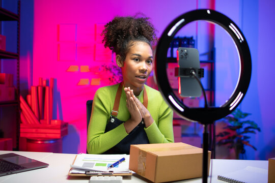 Small online sellers are live-streaming their sales.Young woman confidently films an online product review in studio. Perfect for influencer marketing and digital content creation.