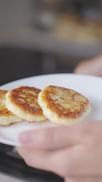 Cottage cheese pancakes are transferred with spatula onto plate after frying