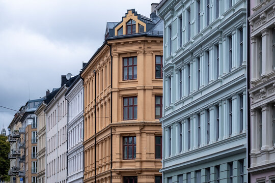 A street in Gr&uuml;nerl&oslash;kka runs between varied buildings, where colorful facades beneath a cloudy sky reveal historic architecture and deep perspective in Oslo, Norway.