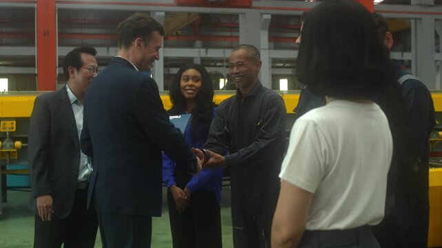 Close-up shot of business partners and industrial engineers shaking hands inside a modern factory. Concept of successful business agreement, international partnership, corporate merger, and B2B manufa