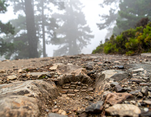 Fototapeta premium Hiking boot footprint in dirt on a rocky trail, foreground detail, outdoor adventure path, wilderness hiking track, mountain forest trail, trail exploration.