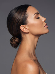 Elegant side profile portrait of a beautiful woman with her dark hair styled in a sleek low bun © paultarasenko