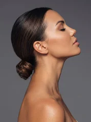 Elegant side profile portrait of a beautiful woman with her dark hair styled in a sleek low bun © paultarasenko