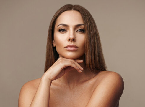 A sophisticated beauty shot featuring a woman with sleek, straight chestnut hair gazing intently at the camera