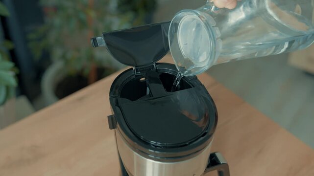 A jug of water is poured into the coffee maker. The coffee preparation stage. Preparation for cooking.