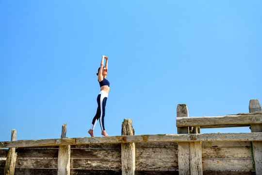 Fit woman stretching outdoors at the beach, warm up exercise routine