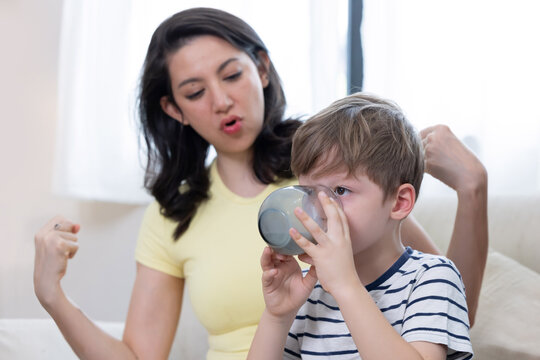 Mother and son sharing a moment while he drinks milk from a glass in their home