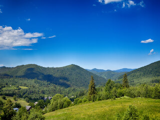 Fototapeta premium Sunny Carpathian peaks: green valleys and cloudy white skies.