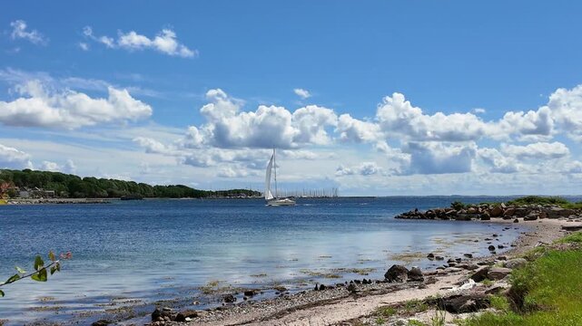 Sailing yacht on Flensburg Fjord near Sonderborg beneath dramatic clouds with calm Baltic Sea water and a peaceful summer atmosphere.