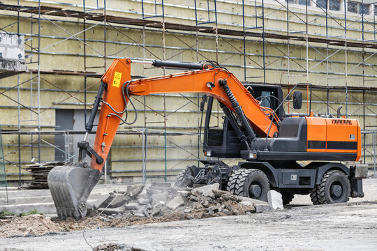 An excavator removes debris at a construction site in the city. Workers oversee the process as construction progresses during daylight hours
