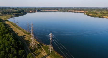 Obraz premium Aerial View: High-Voltage Power Lines Beside Serene Lake 