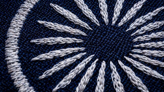 Intricate silver thread embroidery forming a sunburst pattern on a deep navy blue fabric textile surface
