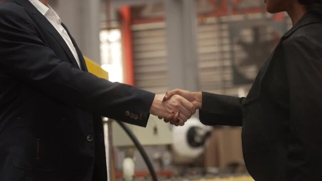 Medium shot of a Caucasian male executive and a Black female manager wearing safety helmets while reviewing operational data on a digital tablet in a heavy industrial plant. Concept of corporate 
