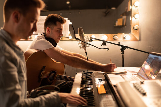 Male Song writer creating song with friend. Men in sound studio