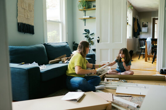 mom and daughter in their living room at home assembling furniture