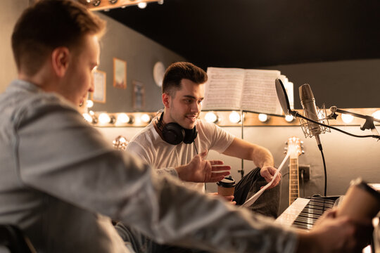 Male Song writer discussing lyrics with colleague. Men in sound studio