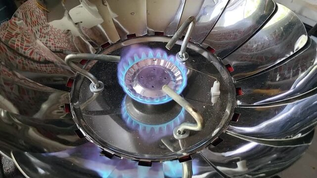 A round metal gas burner with blue gas flames.