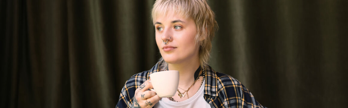Young beautiful non binary person enjoying a cozy moment in a cafe with warm vibes