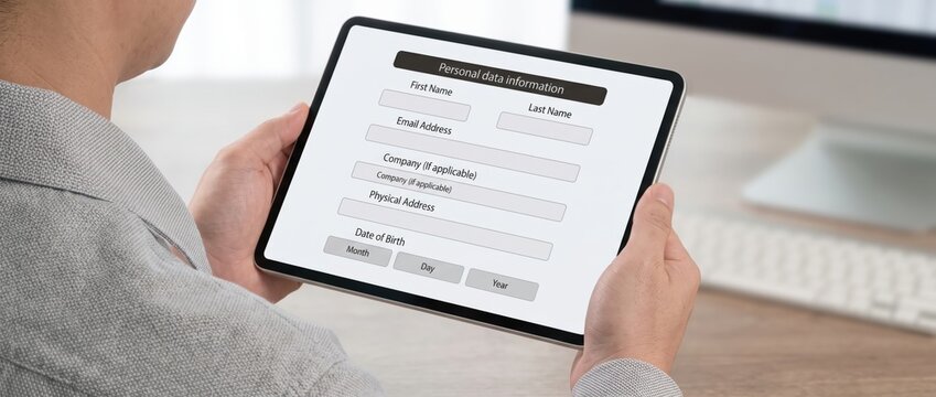 Professional filling out digital personal data form on tablet screen in office environment for secure identity verification with computer complete digital