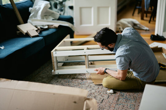 man in his living room at home assembling furniture