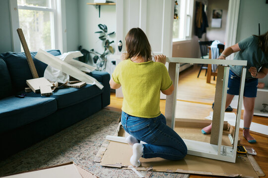 mom and daughter in their living room at home assembling furniture