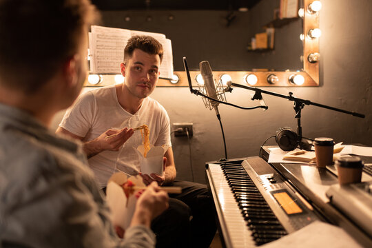 Musicians having lunch in studio. Men in sound studio