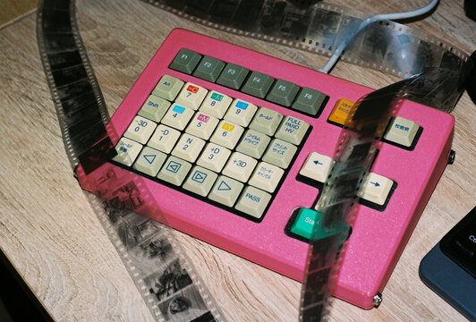 Bright pink keyboard overlaid with tangled 35mm film negatives