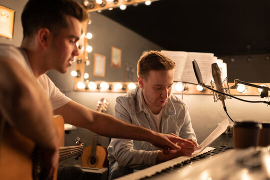 Male Song writers making notes together. Men in sound studio