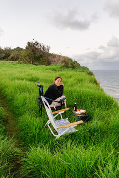 UGC woman at sunset picnic with camping chairs on coastal lookout