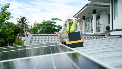 Asian Engineer Inspecting Solar Panels on Residential Rooftop with Laptop and Toolbox © Prathankarnpap