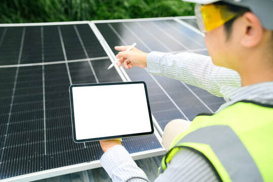 Engineer inspecting solar panels with digital tablet blank screen mockup at renewable energy installation site