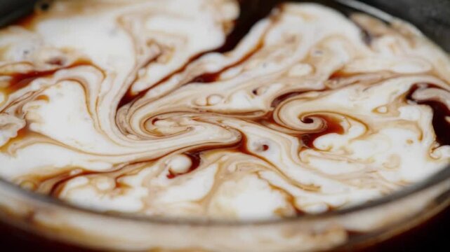 Coffee cream swirl beverage foam brown white cup closeup texture, milk pour creates marbled pattern in dark coffee with smooth motion and rich contrast for cafe drink preparation refreshment