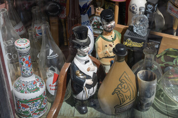 Obraz premium old brand glass bottles and ceramic whisky decanters in the shop window of Ralph's Hardware, a second hand store, located at 840 College St, Toronto