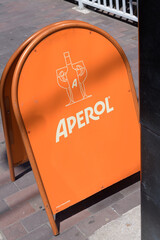 Obraz premium rounded, shaped, orange a-frame with brand advertising of Aperol, an alcoholic aperitif, on a sidewalk in Toronto