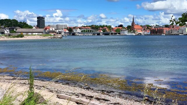 View of Flensburg Fjord near Sonderborg featuring a sandy beach, historic city, calm water along the Baltic coast.