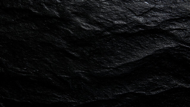 Closeup of rough textured black stone surface for backgrounds and design elements