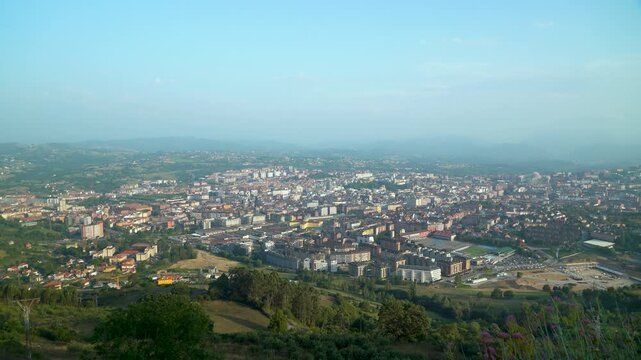Vista panor&aacute;mica de Oviedo con el casco urbano, edificios, tejados y monta&ntilde;as al fondo, mostrando el paisaje caracter&iacute;stico de la capital asturiana.