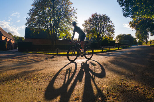 Cyclist riding bicycle on country road during golden hour